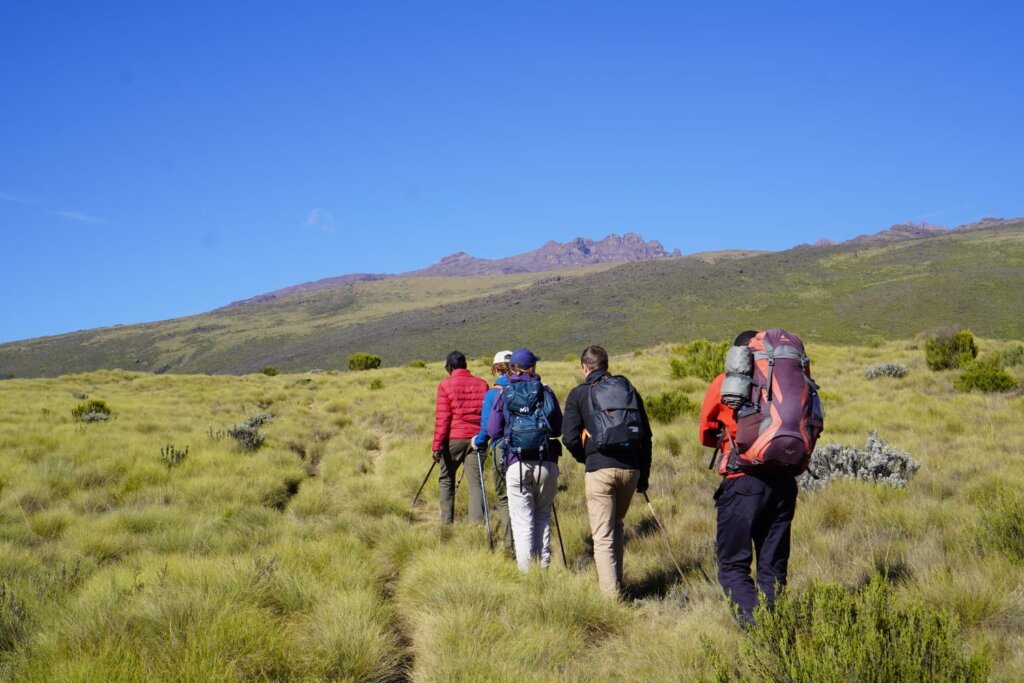 Hikers trekking across rugged volcanic terrain at Mount Suswa