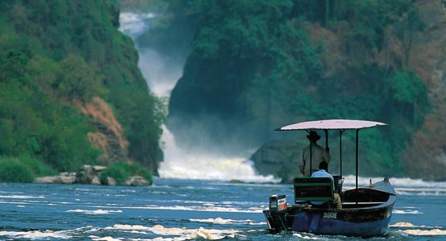 Tour boat approaching Murchison Falls with roaring waterfall in the background