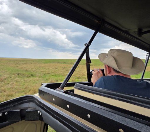 kenya safari - Photographer using a 150-600mm telephoto lens to capture a lion on a Kenyan photographic safari.