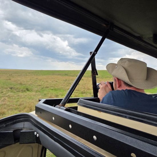 kenya safari - Photographer using a 150-600mm telephoto lens to capture a lion on a Kenyan photographic safari.