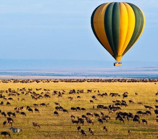 Hot air balloon flying over Maasai Mara at sunrise in luxury experience safari package
