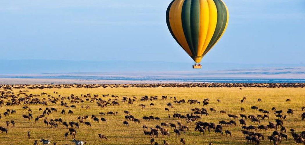 Hot air balloon flying over Maasai Mara at sunrise in luxury experience safari package