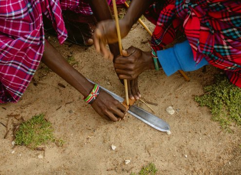 The Maasai lighting a fire with sticks on a budget safari in masai mara kenya